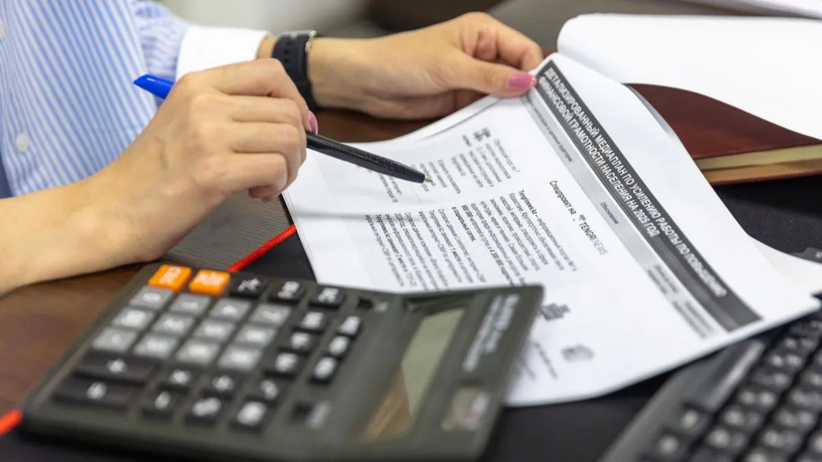 Hands reviewing a tax form beside a calculator for collecting W-9s and issuing 1099s