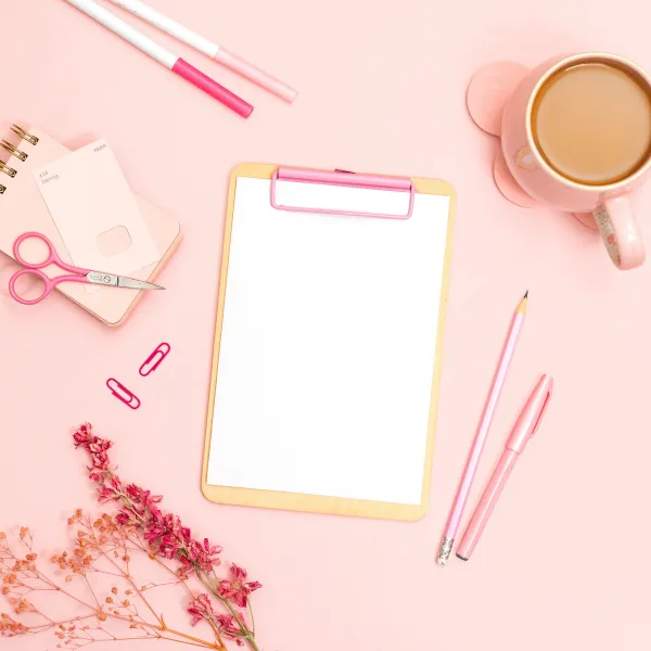 Clipboard and office supplies on a pink desk for using margins to set prices