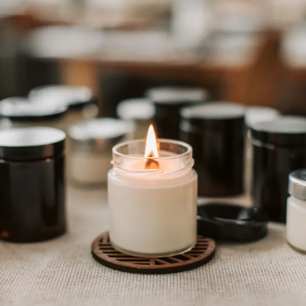 Lit candles in glass jars on a table for using margins to set prices